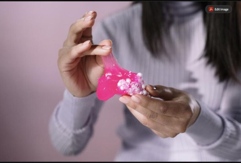 Close-up of hands stretching pink DIY slime with beads, a classic sleepover craft activity (stock photo, used for illustration)
