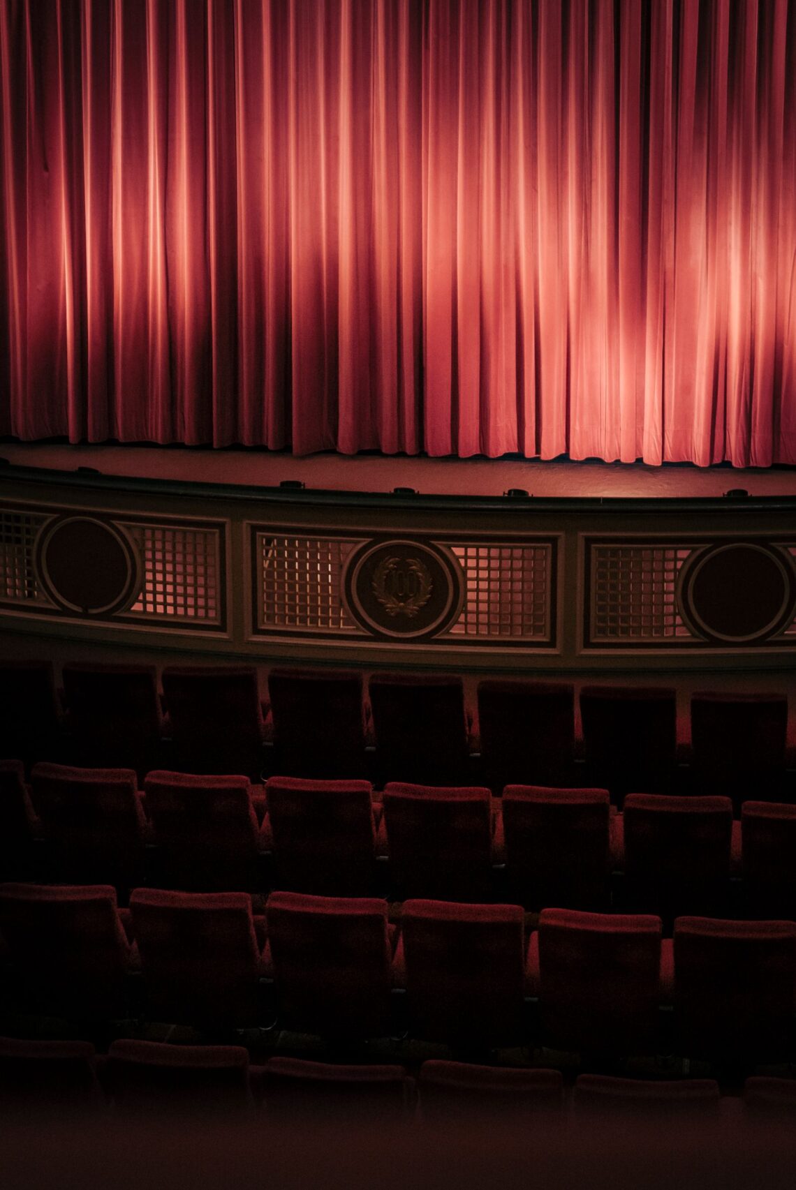 Ornate red velvet curtain and empty seats inside a live theater, similar to the venue where the theater-themed birthday play was held