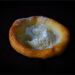 A golden, puffed pastry with a hollow, eggy shell and a dusting of powdered sugar on a dark background (stock photo, used for illustration)