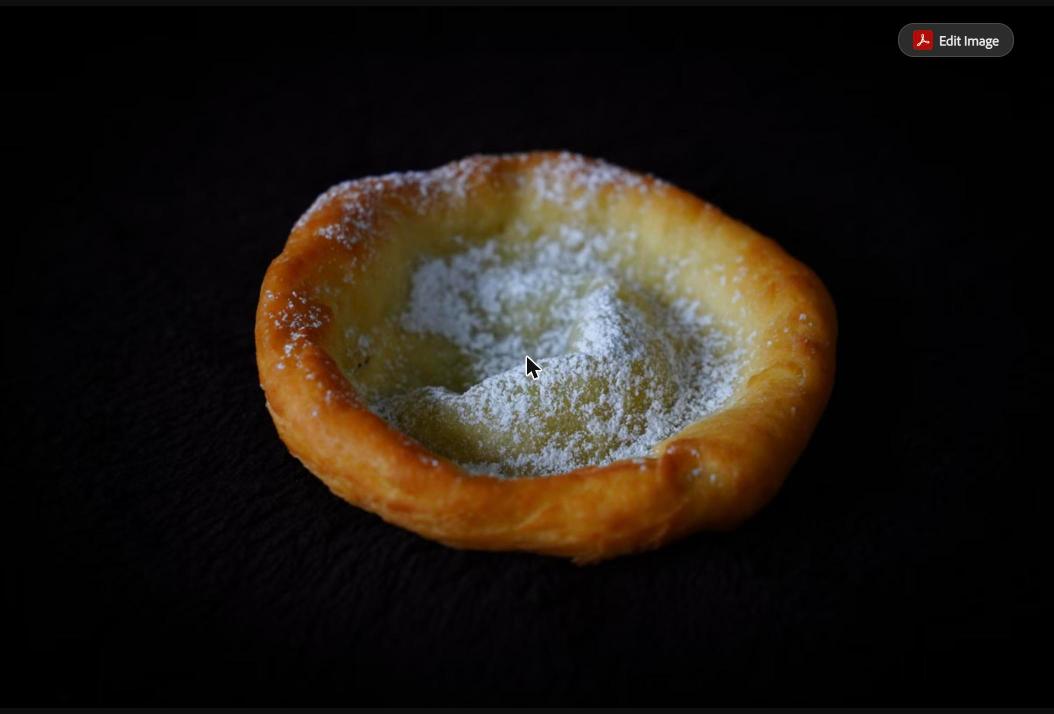 A golden, puffed pastry with a hollow, eggy shell and a dusting of powdered sugar on a dark background (stock photo, used for illustration)