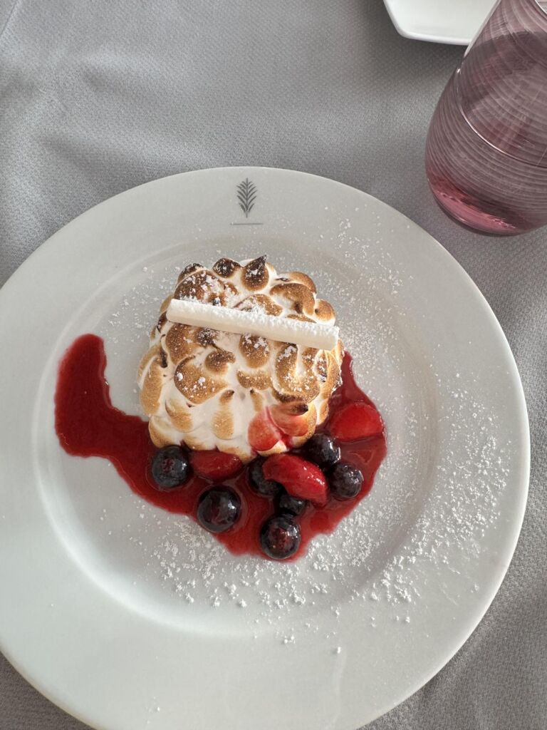 A baked Alaska dessert with toasted meringue and fresh berries, served in the Luminae dining room.