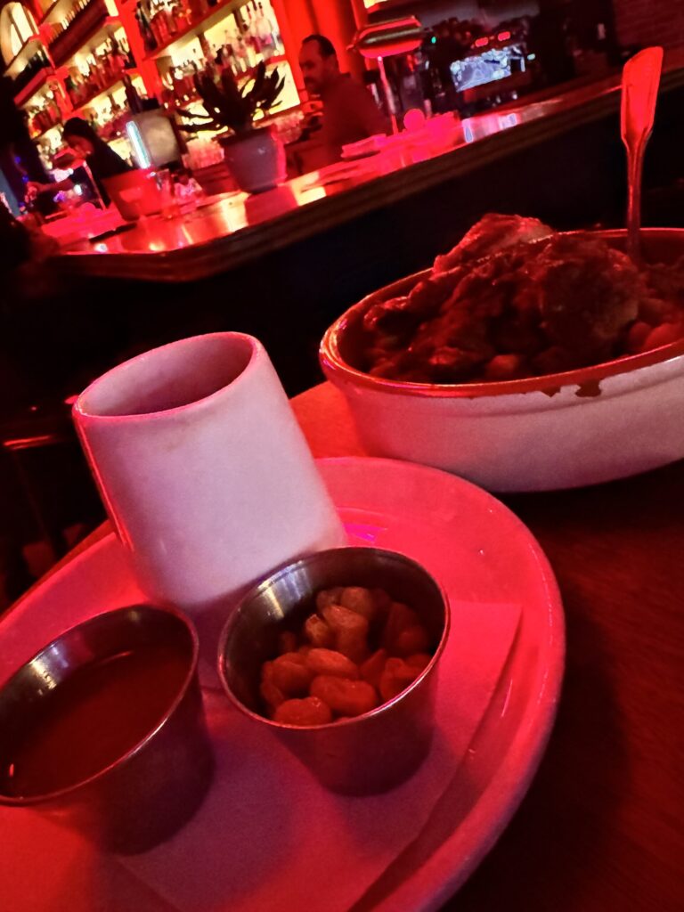 Moroccan Couscous Royal with lamb and its sides under the red bar lights at Massilia in Santa Monica