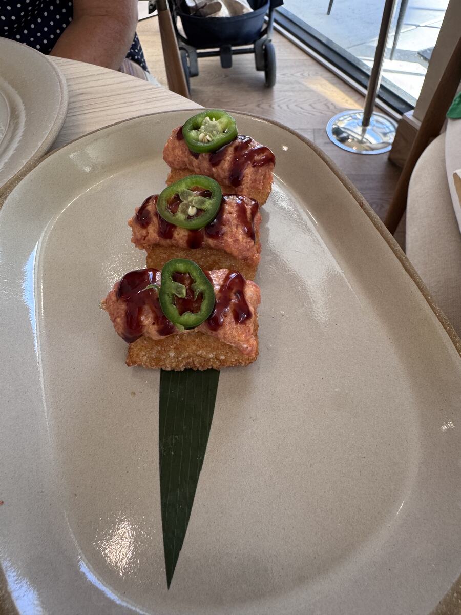 Spicy tuna hand rolls drizzled with sauce and topped with jalapeño