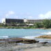 Turtle Bay Resort hotel building on its coastal point, with waves breaking on the rocky shoreline in the foreground