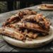 A stack of smoky barbecue pork ribs on a wooden plate (stock photo, used for illustration)