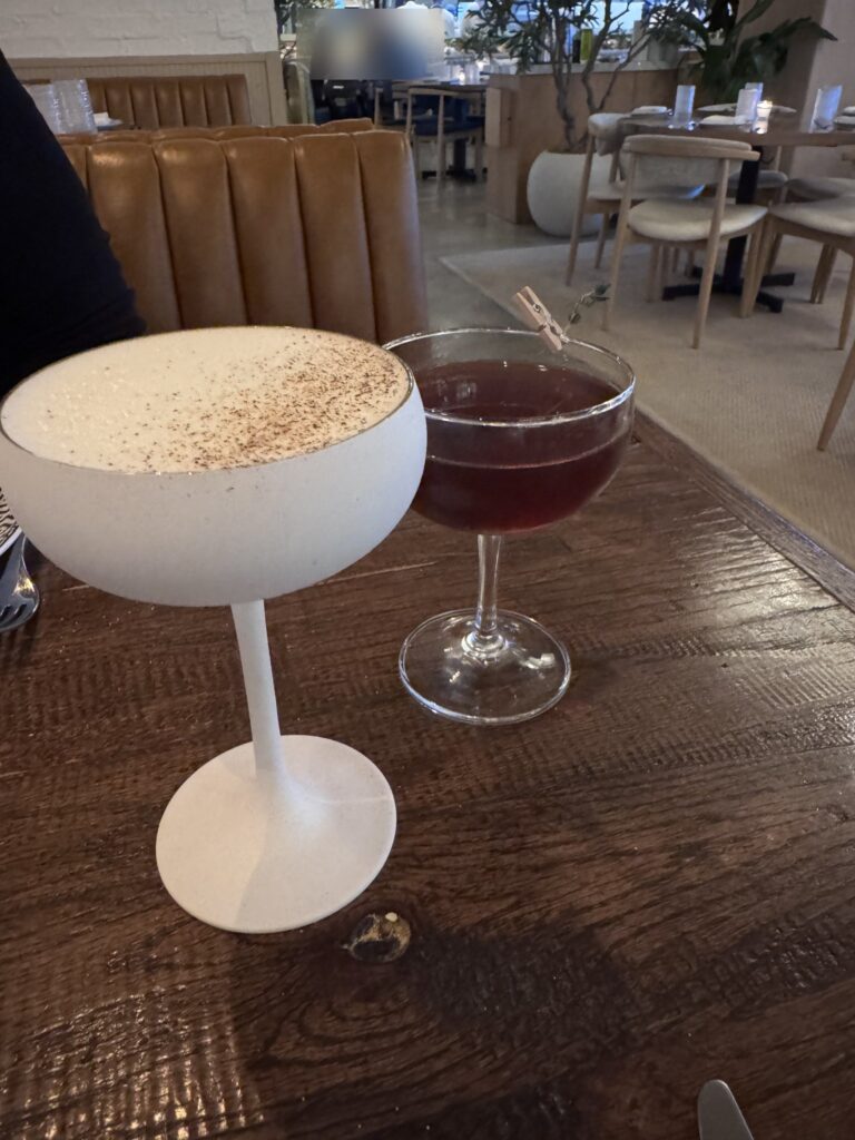 Minoan Sour with egg white foam and an Ankara Rye Club cocktail on the table at Zaytinya