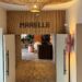 The entrance to Marelle in Santa Monica, with the restaurant name on a wood-paneled wall, a woven pendant light overhead, and open doors leading to a stone-floored dining room