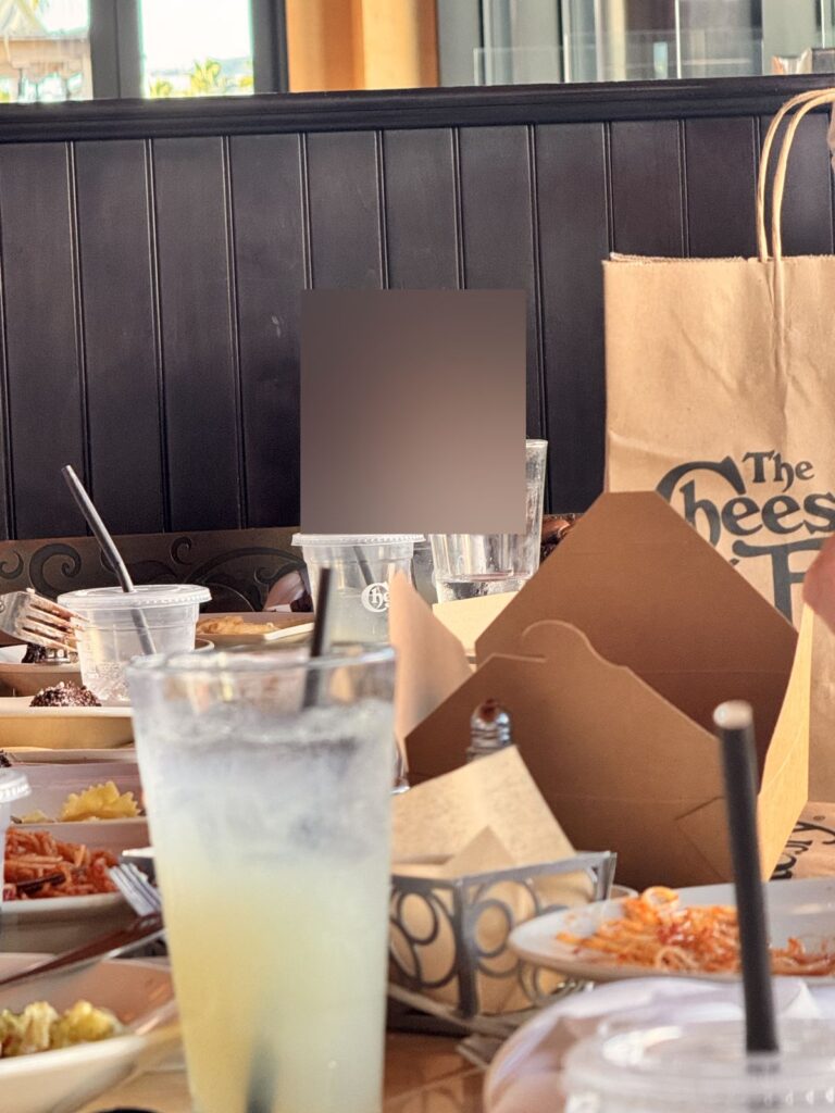A table full of empty plates and to-go boxes at The Cheesecake Factory