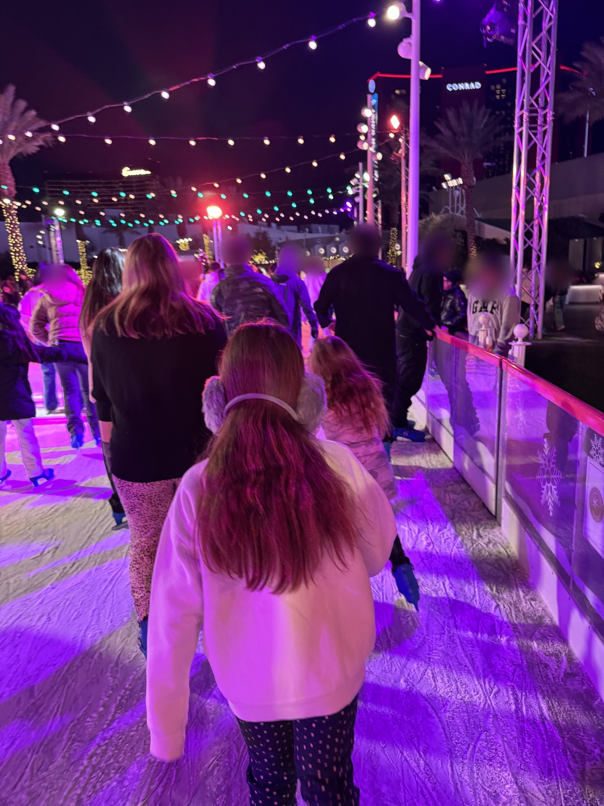 Skaters on the Fontainebleau Las Vegas holiday ice rink at night under string lights