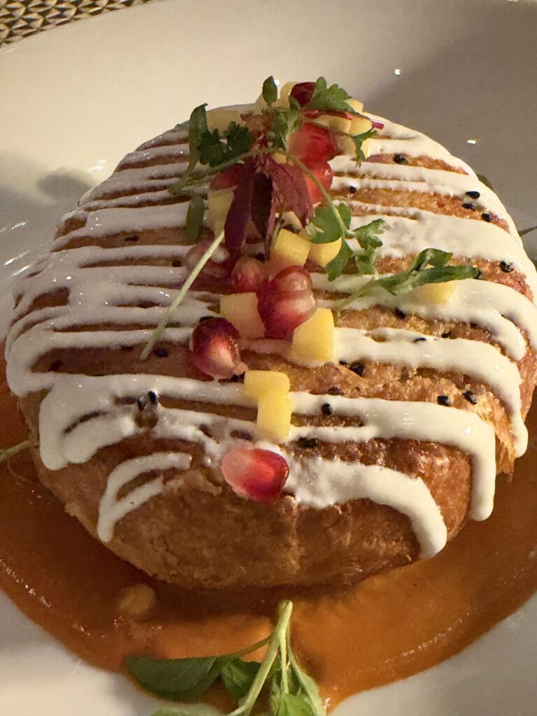 Masala paneer en croute, a puff pastry dome with yogurt and pomegranate, at Kahani