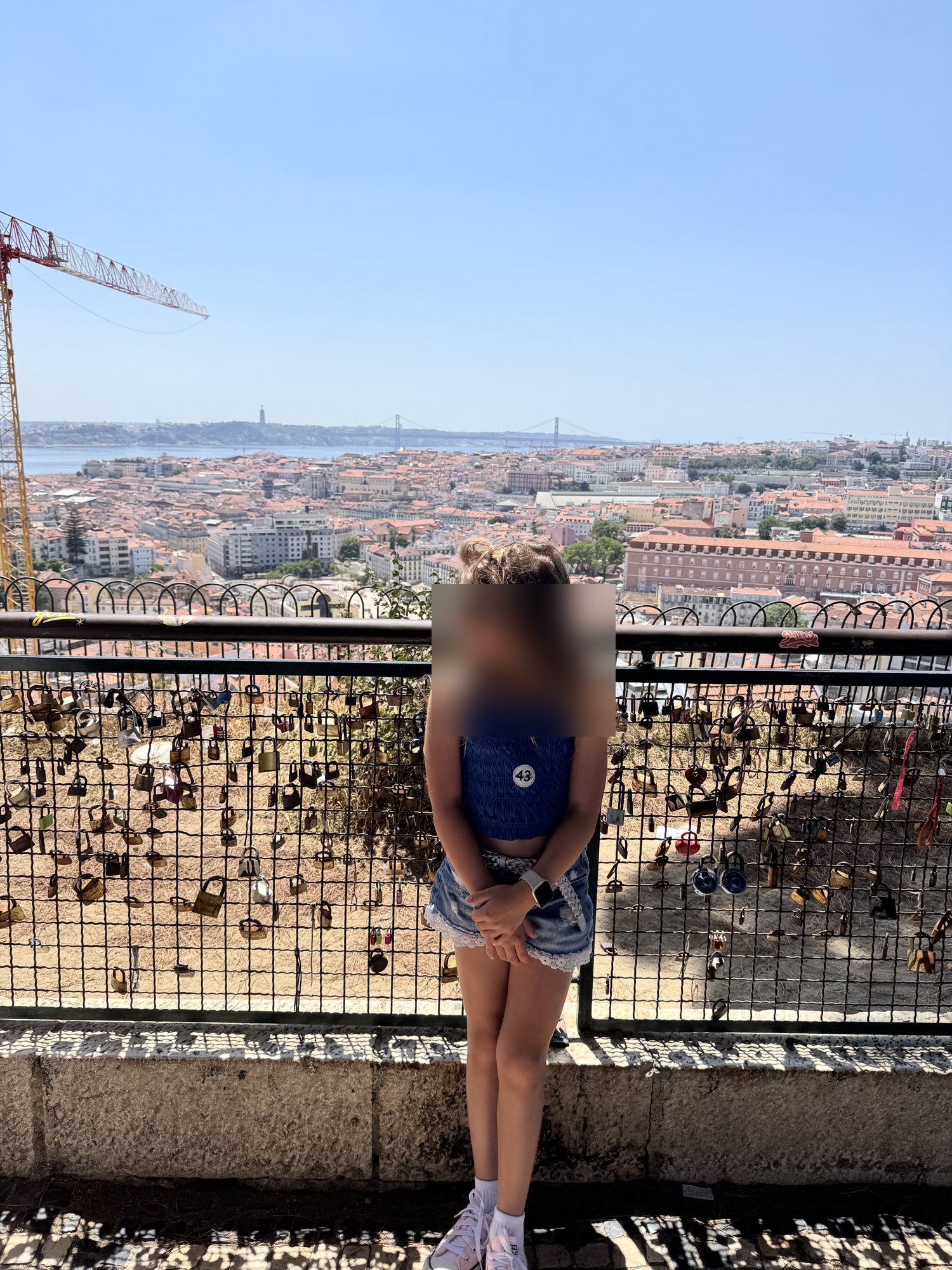 Girl at a viewpoint stop on our Lisbon tuk tuk tour, with love locks and the city behind her