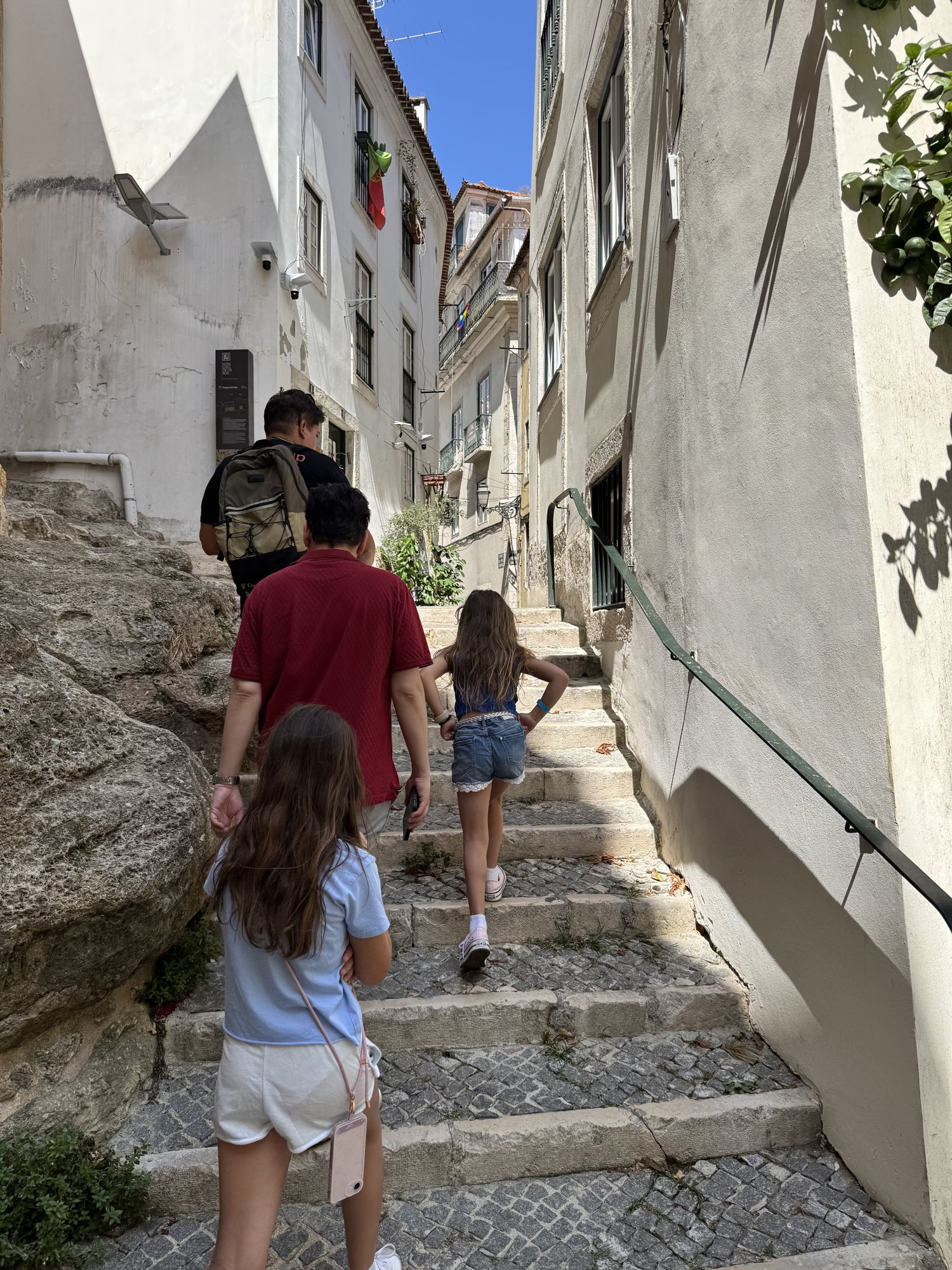 Family walking up a steep stone stairway in Lisbon