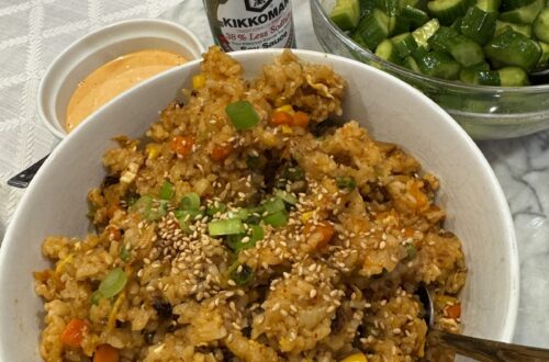 A big bowl of kimchi fried rice with a bowl of smashed cucumbers and spicy mayo