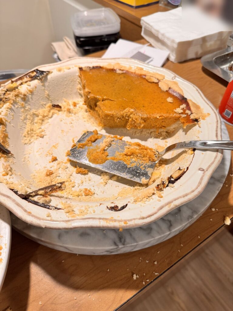 A homemade pumpkin pie, mostly eaten, in a white pie dish