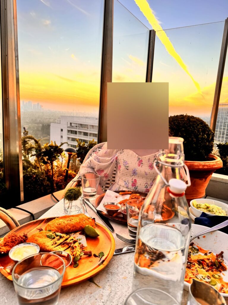 Our daughter at dinner on The Roof at sunset, face blurred