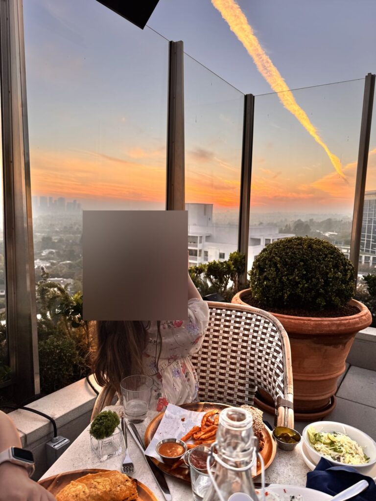 Our daughter photographing the sunset from our table at The Roof, head blurred