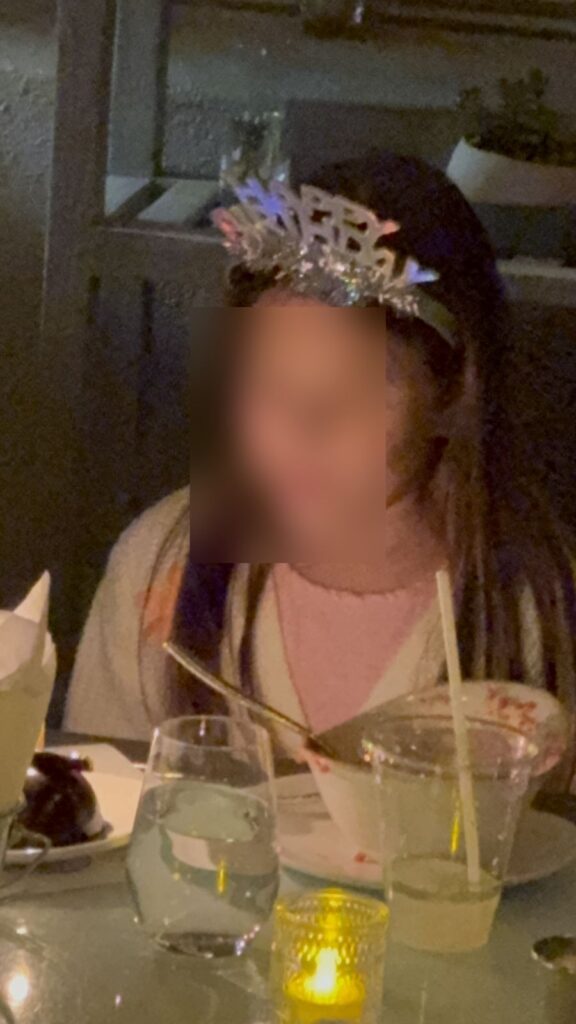 Birthday girl in a tiara at a candlelit dinner table after the theater