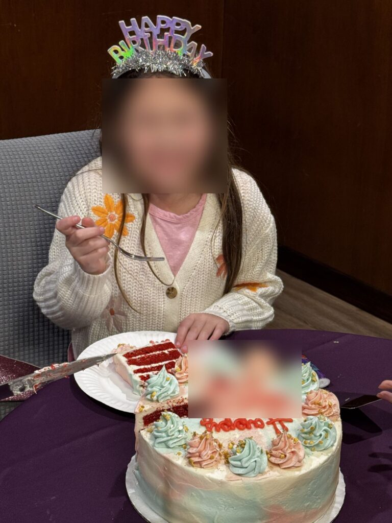 Birthday girl in a tiara with a red velvet SusieCakes birthday cake