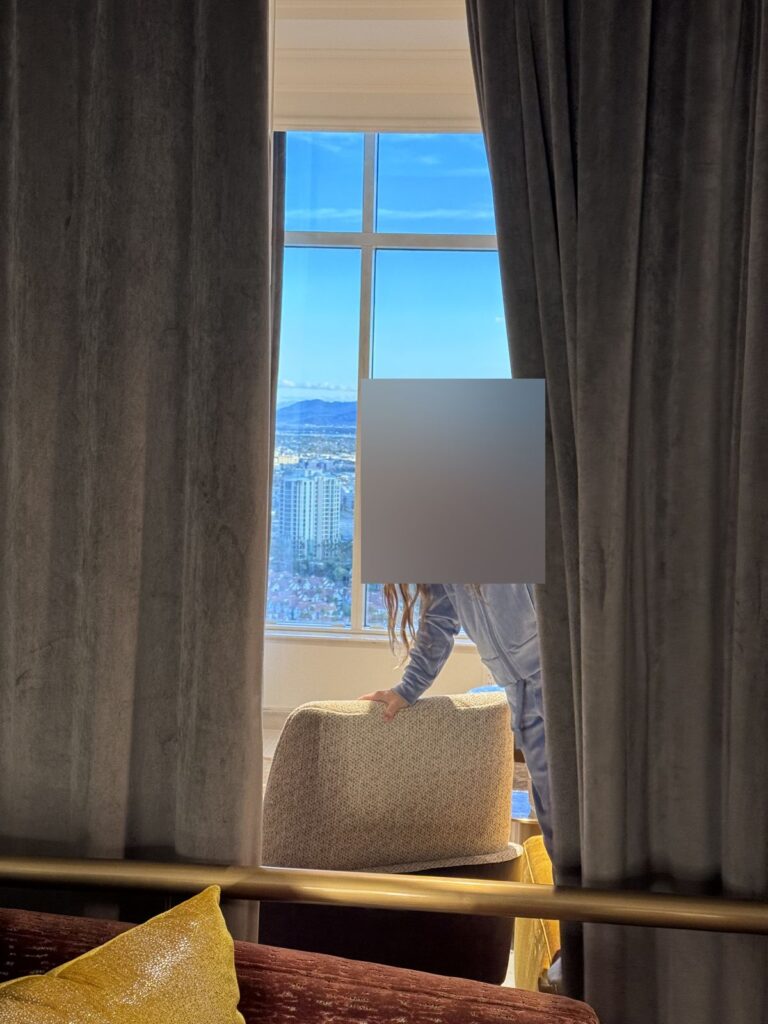 Child at the suite window at The Venetian with mountains and the city behind her